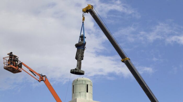 A crane removes a confederate statue.