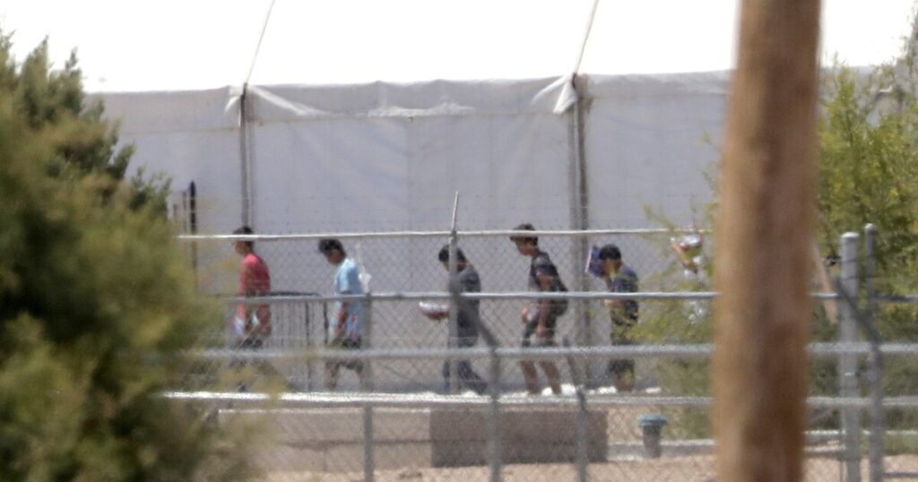 A photo of six individuals walking across a bridge in what appears to be a prison.