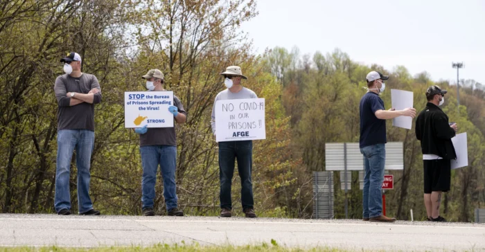 Men in masks stand in a picket line during a protest.