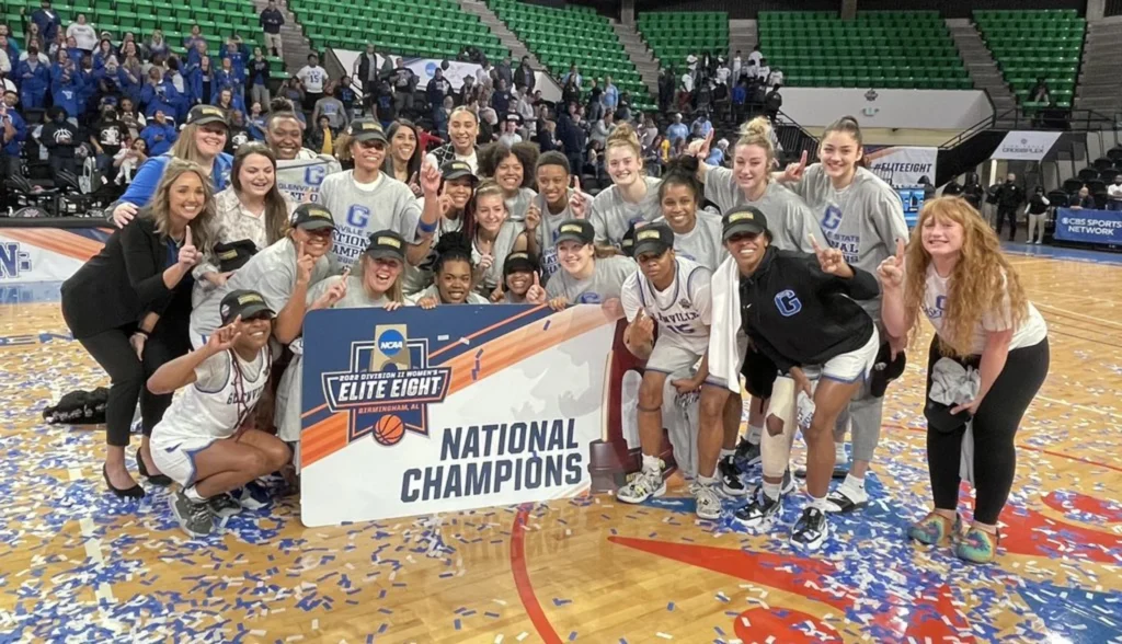 Several young women are seen on a basketball court holding a sign and posing for a photo.