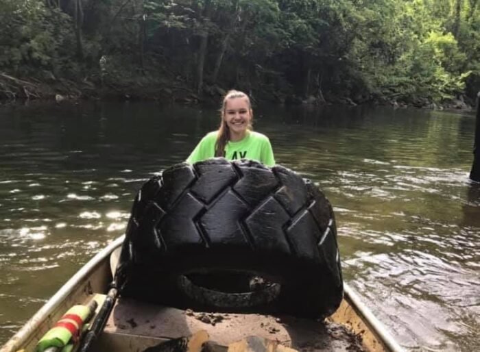 Lilly Bias on a river collecting trash after being inspired by Michelle Martin and the Trash Your Kayak Clean Up Crew. 