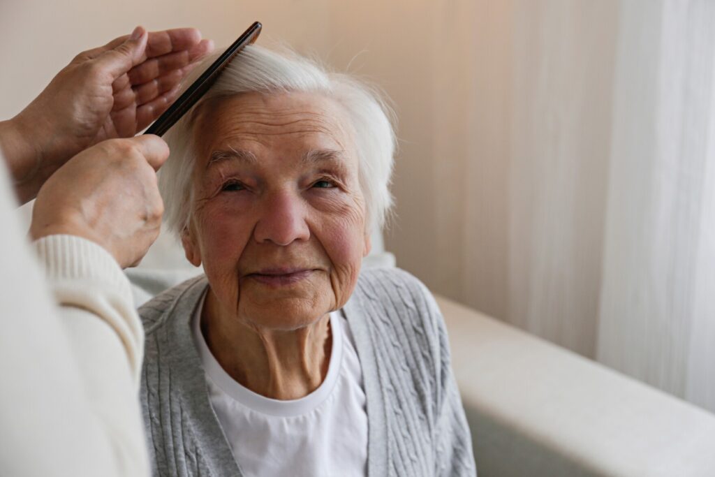 Elderly woman having her hair brushed.