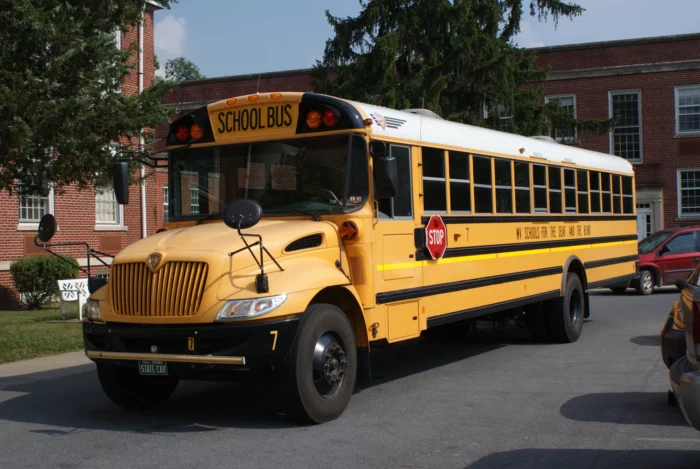 A yellow school bus driving away from a school.