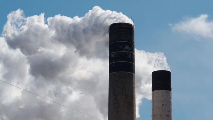 To black and white colored smokestacks releasing steam into the sky.