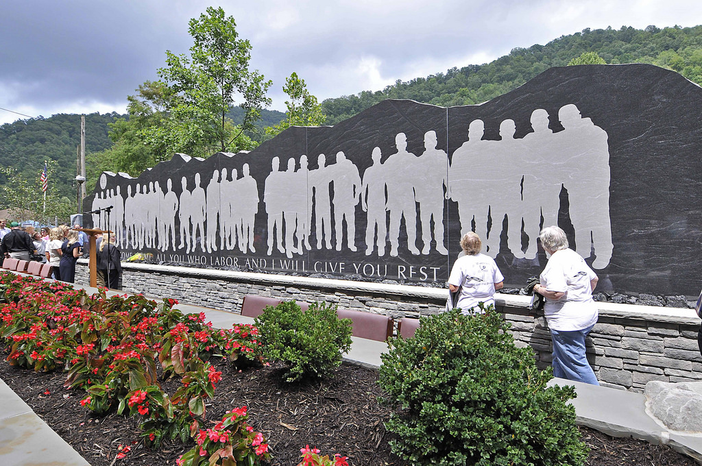 Visitors look at the gray silhouettes of miners on the dark stone memorial to those killed in the Upper Big Branch disaster in 2010.