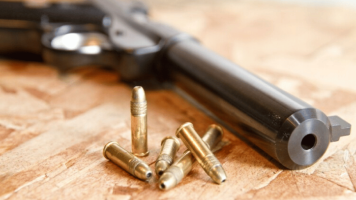 A gun on a table with bullets next to it.