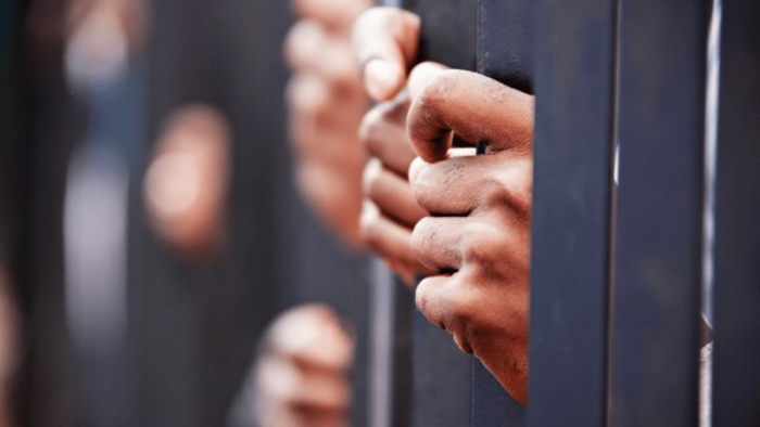 hands hold onto jail bars