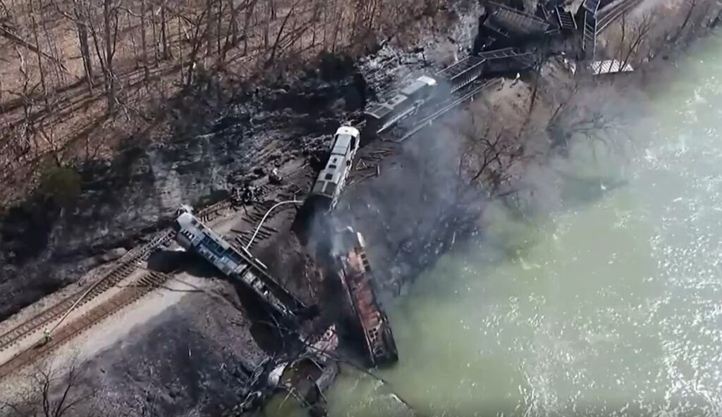 Charred CSX locomotives lie on their sides, with one in the water, along with jumbled empty coal hoppers at Wednesday's derailment site.