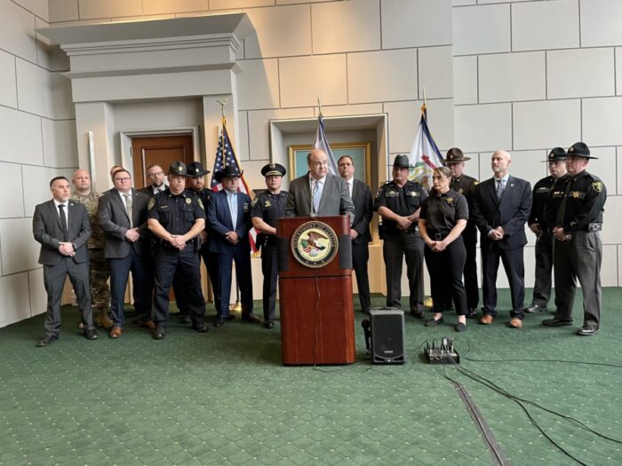 Law enforcement officers stand behind a podium announcing the largest drug bust in the state of West Virginia