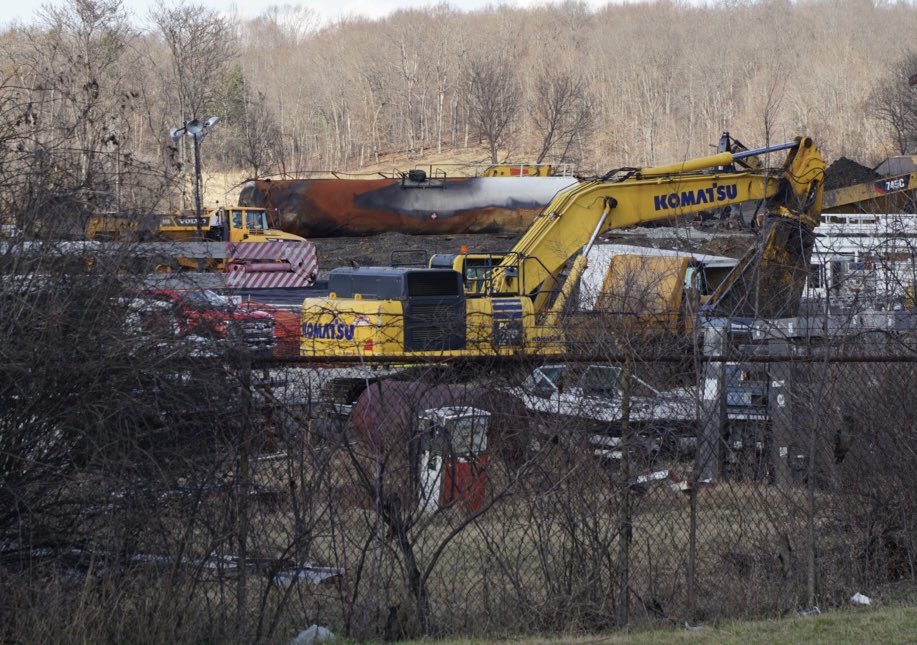 A burned up railroad tank car is seen behind a yellow piece of construction equipment in East Palestine, Ohio.