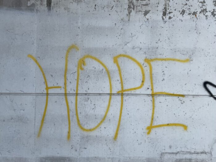 The word "HOPE" in all caps is seen on a concrete wall. The letters are yellow.