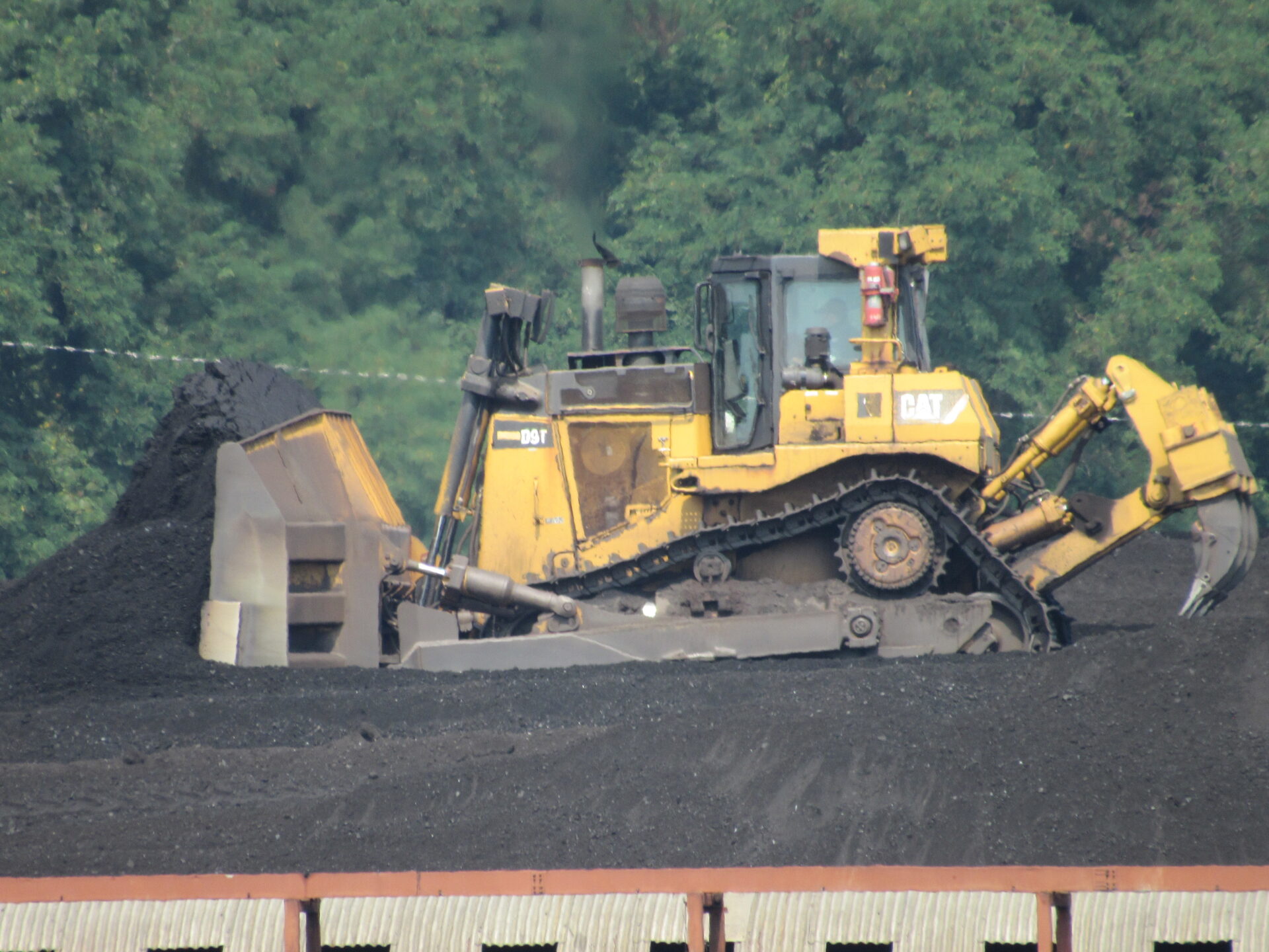A yellow bulldozer moves a mound of black coal at a power plant in West Virginia.