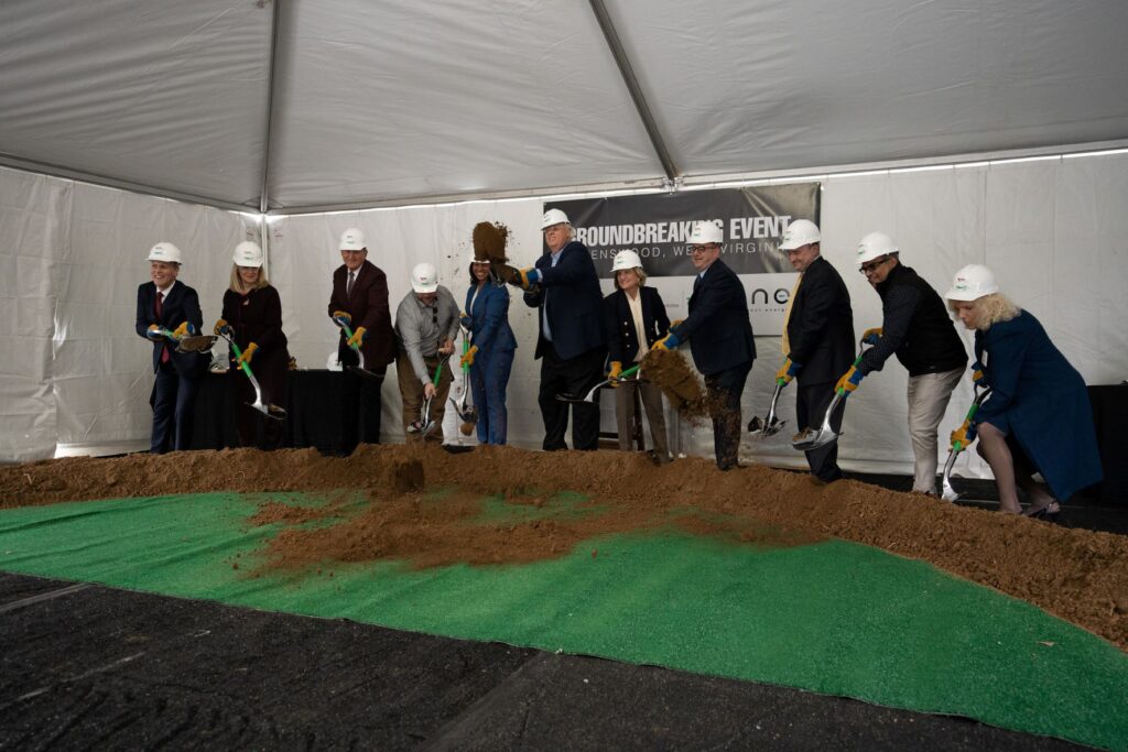 Gov. Jim Justice throws a big shovelful of dirt at the groundbreaking for the Berkshire Hathaway Energy project in Jackson County, wearing a hard hat and surrounded by other state and federal officials in hard hats, shovels in hand.