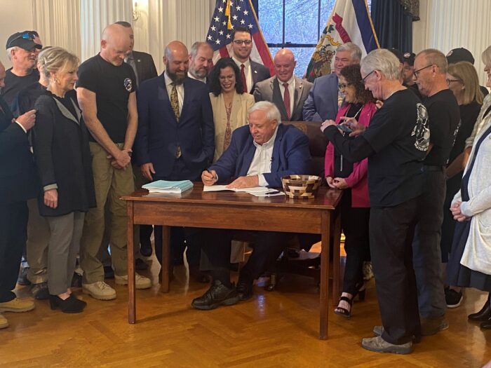 Lots of people surrounding the governor as he signs a bill into law.