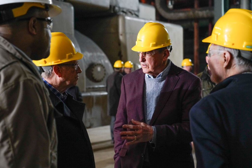 Sen. Joe Manchin and Bill Gates, both wearing yellow hard hats, toured the closed Kanawha River power plant in Glasgow. Both are seen in a space with some old, decommissioned power plant machinery.