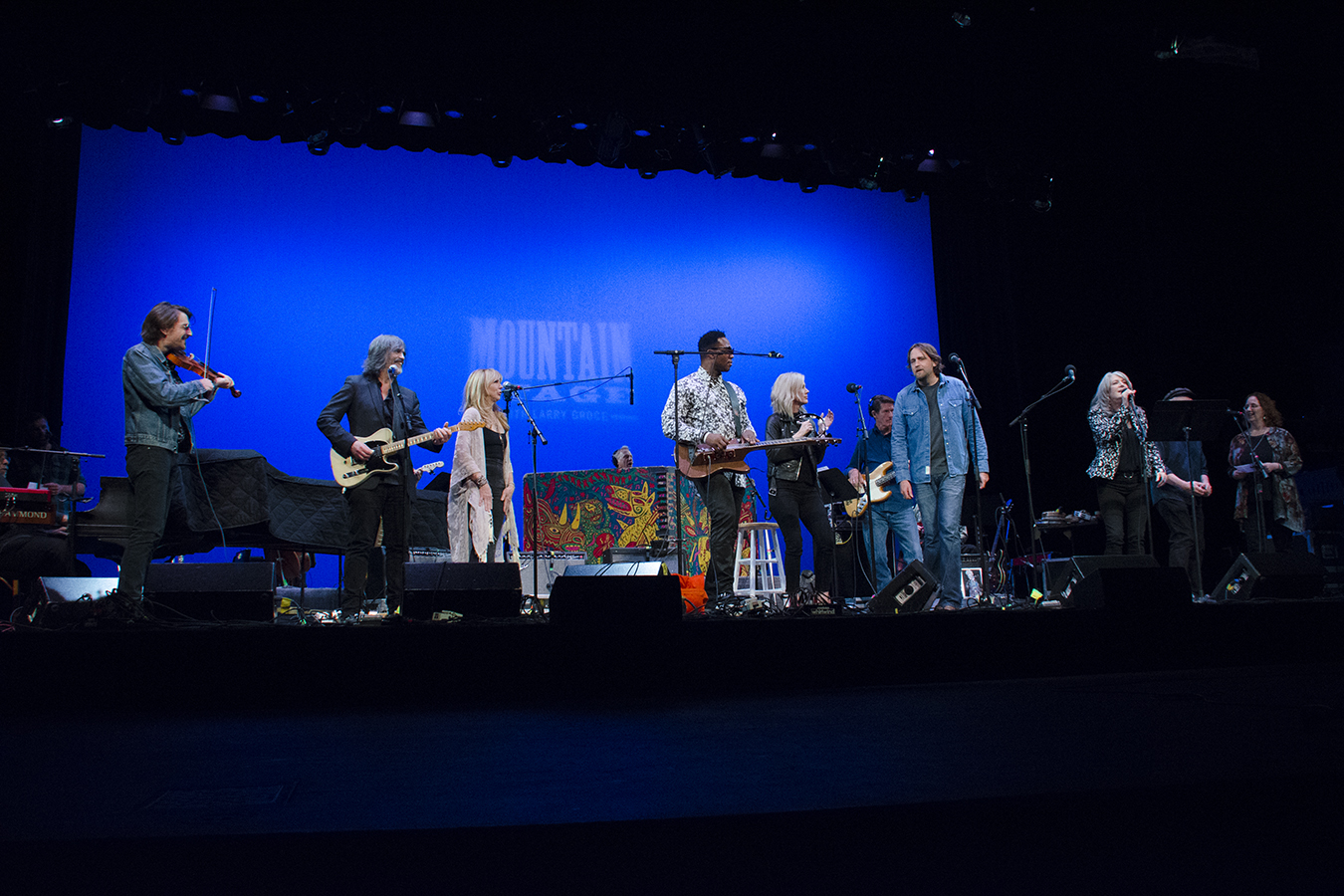 Eight people, musicians stand side by side on the Mountain Stage.