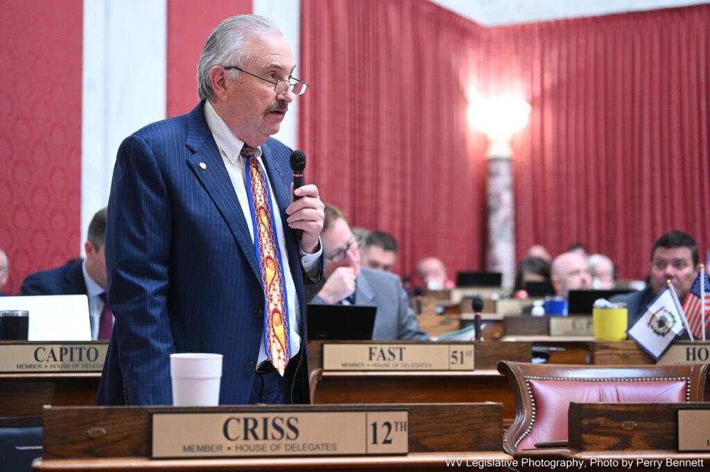 Gray-haired man with flashy tie stands and speaks on House floor.