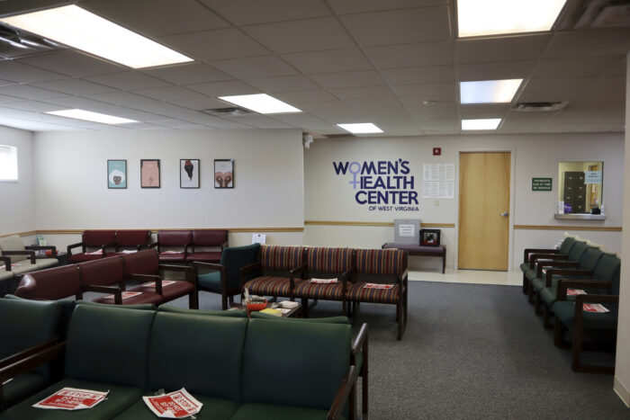 A doctors office waiting room with empty green and red chairs.