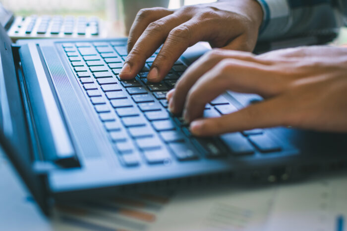 Hands are poised on the keyboard of a laptop ready to write.