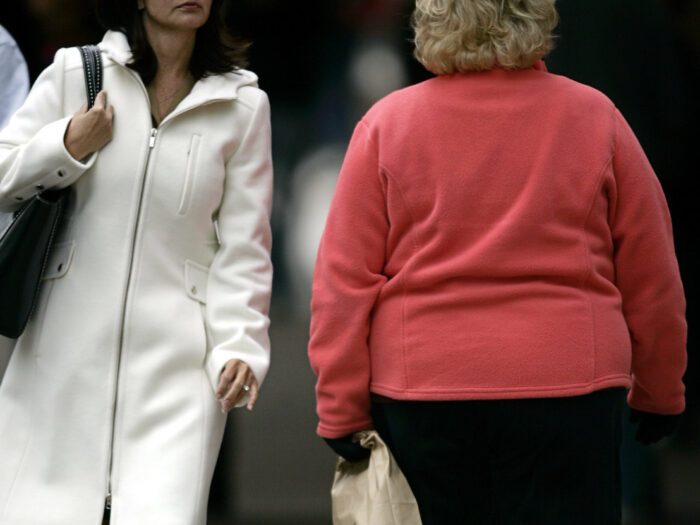 Two women walk past each other.