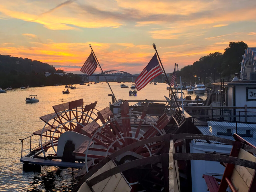 Sternwheel driven riverboats with a sunset behind them.