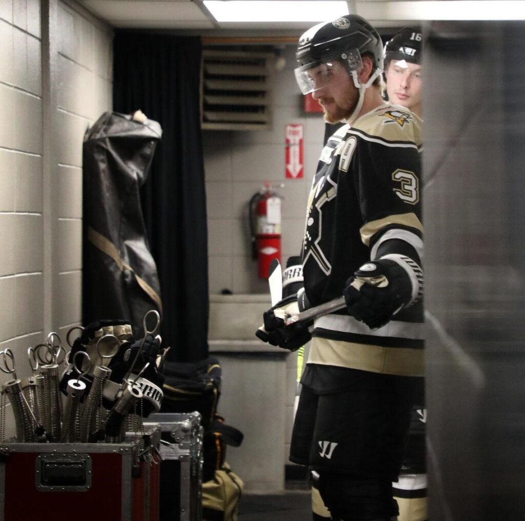 A male hockey player is dressed and ready to take to the ice.