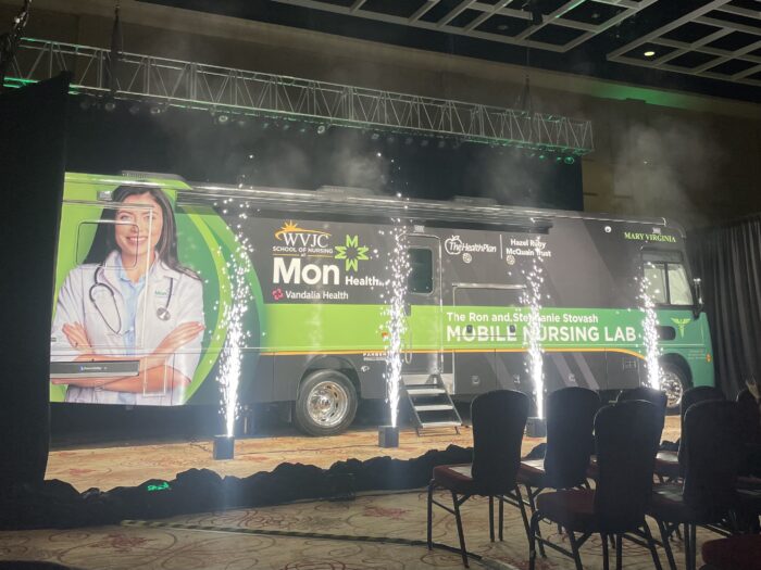 A green and black large RV is seen with celebratory fireworks.