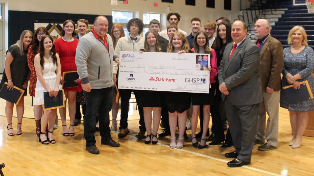 A big group of high school students standing around a big check.