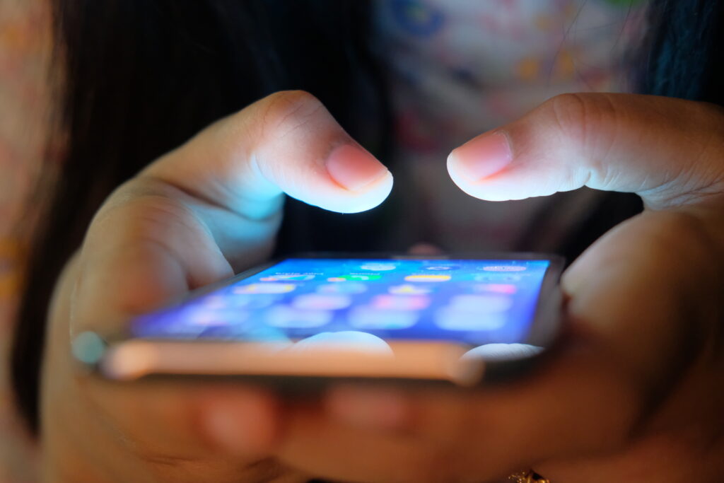 Hands are seen grasping a glowing phone screen.