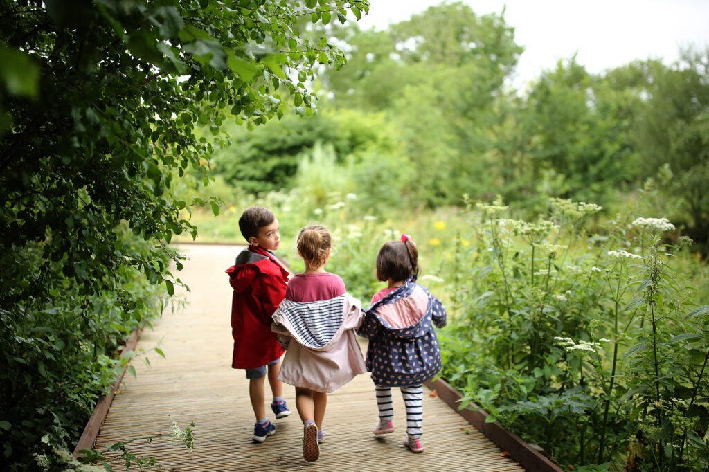 Three children are seen walking a forested path