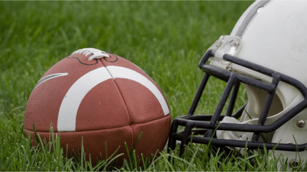 An American football and a helmet on a grass field