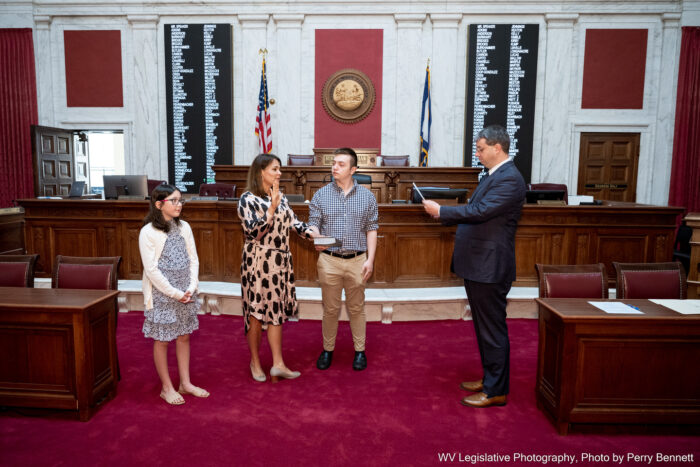 Four people stand side-by-side in the House of Delegates chamber.
