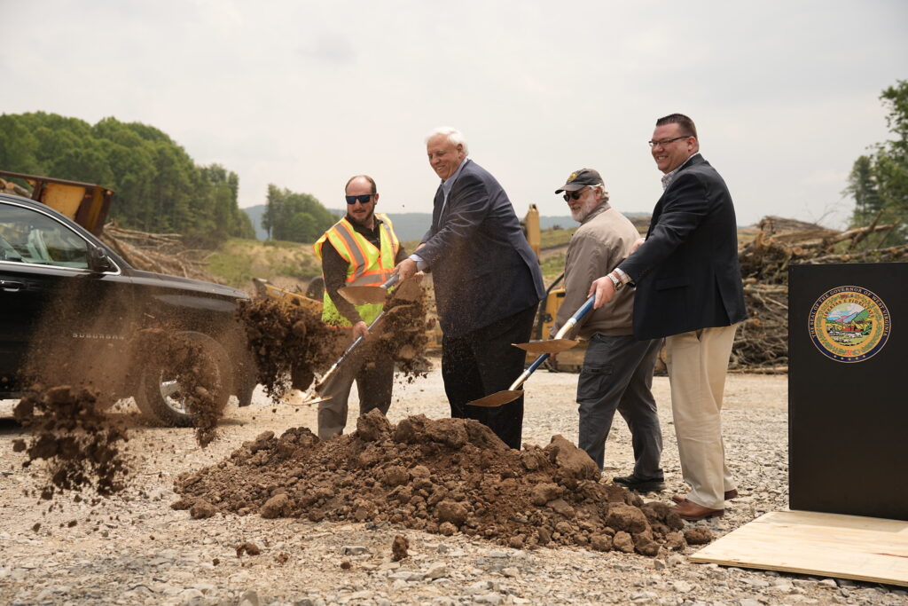 A group of state leaders throw shovels full of dirt in a symbolic groundbreaking for a highway project.