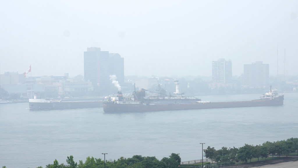 A picture of several freighters moving through smoky haze on the Detroit River in Windsor, Ontario.