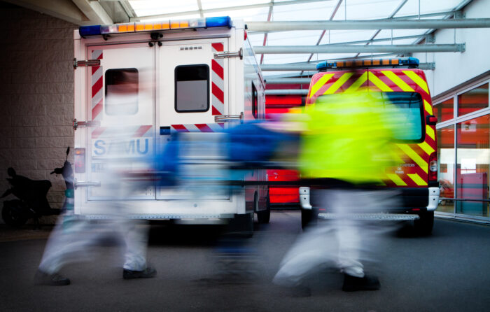 Two emergency personnel rush past emergency vehicles.