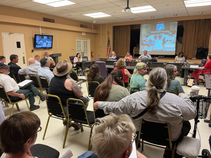 Jefferson County residents sit in rows of chairs facing long table with members of the Jefferson County Commission behind it.