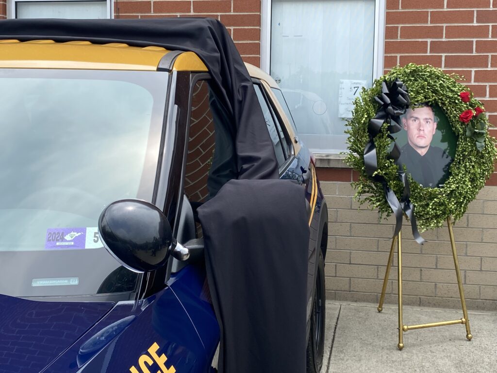State Police cruiser draped in black with Cory Maynard's portrait in a wreath.