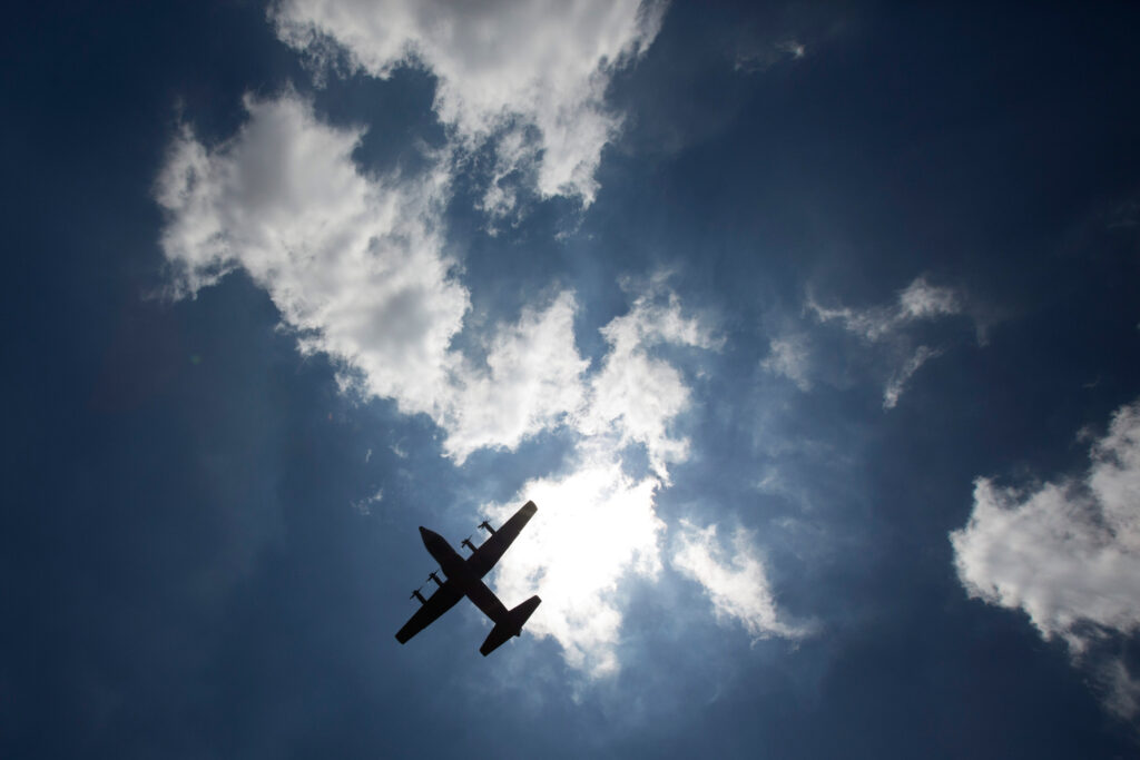 A military aircraft carrying Mandela's body departs from Waterkloof military airbase for the Eastern Cape on Saturday in Pretoria, South Africa. The plane is silhouetted against the bright sun in a blue sky with some white clouds.