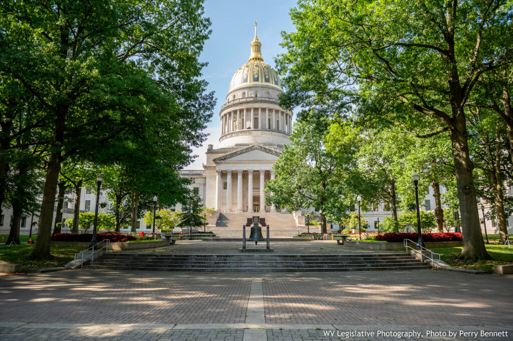 Clear blue sky, West Virginia Capitol Dome in the background with the West Virginia bell in the foreground.