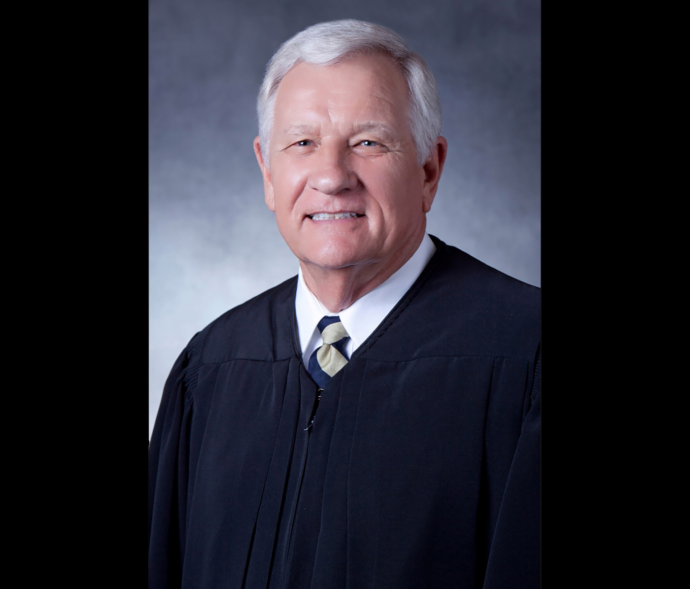 Gray-haired man wearing judge's robes.