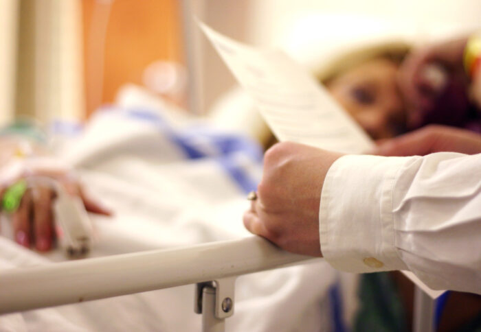 A doctor is seen visiting the bedside of a patient.