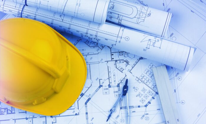 Blueprints construction and a yellow hard hat with a compass.