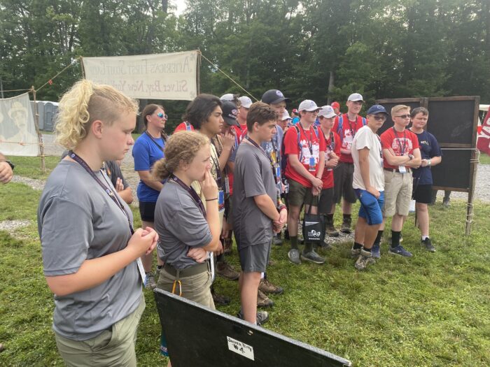 A group of Girls and Boys watching a demonstration outside at a Jamboree camping event.