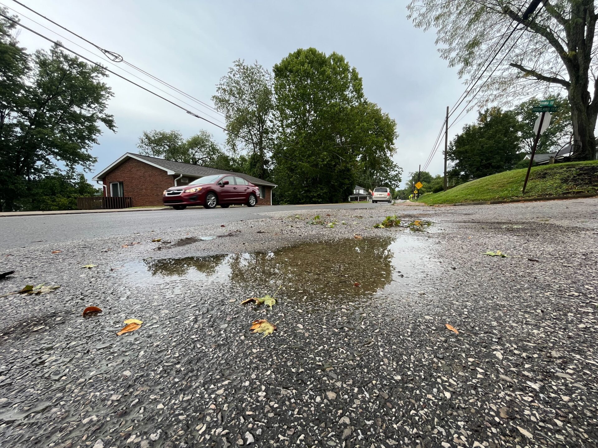 A car drives over wet pavement after a severe summer storm under gloomy skies.