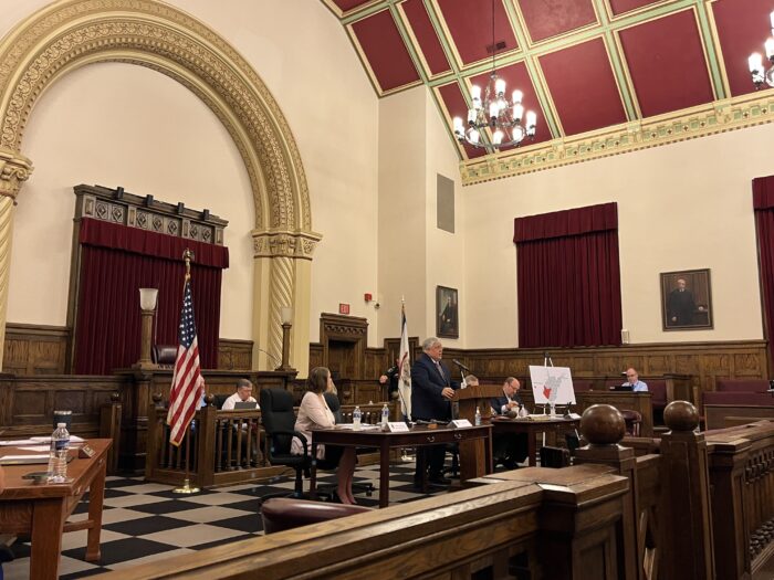 A man speaks at a podium in a courtroom.