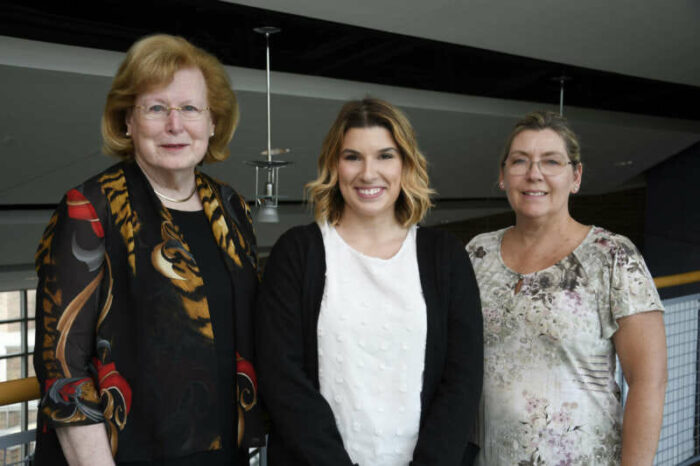 Three women stand together for a photo.