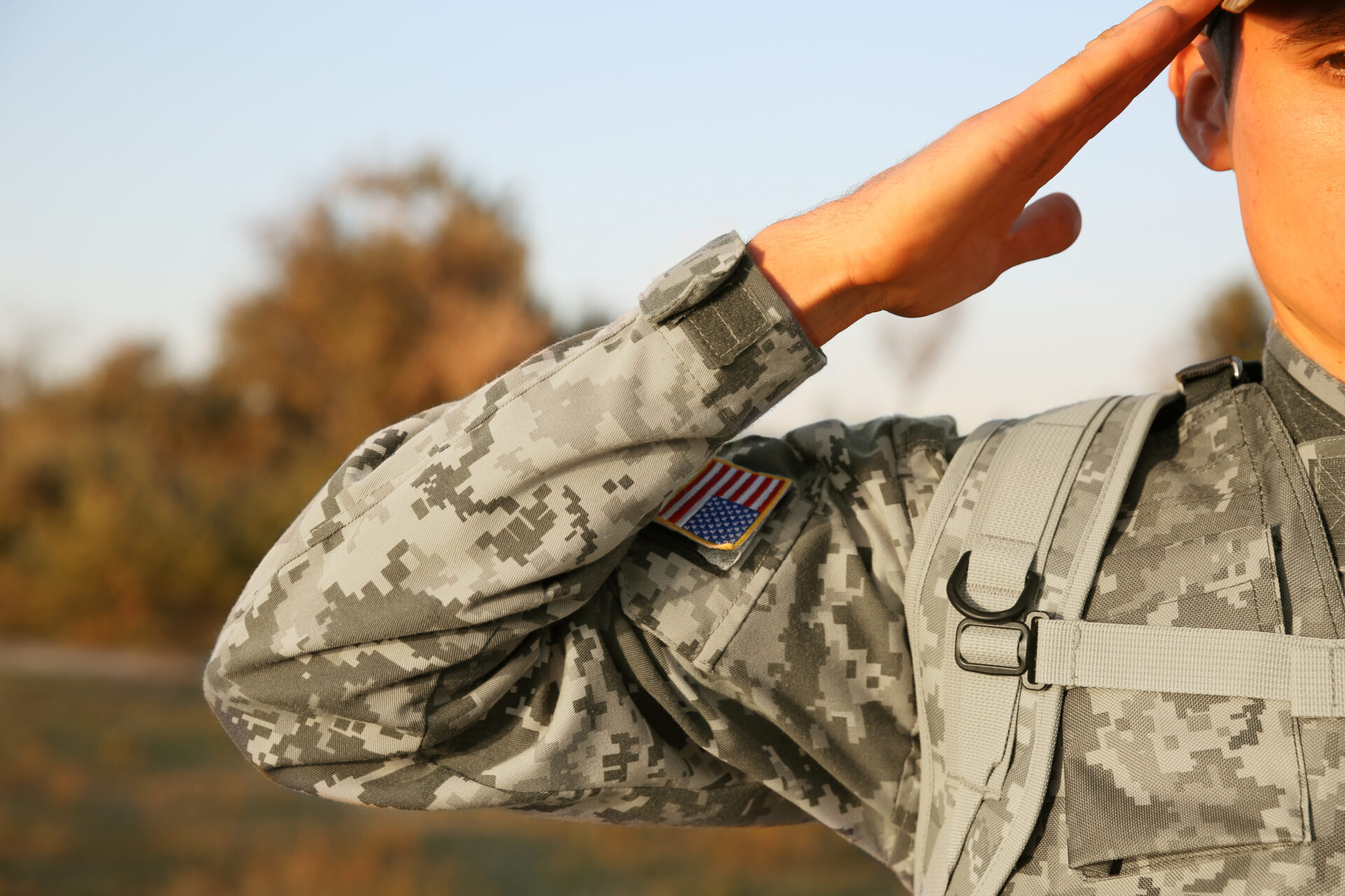 Close up of a U.S. Army National Guard soldier in uniform. An American flag patch can be seen on the soldier's shoulder as they salute.
