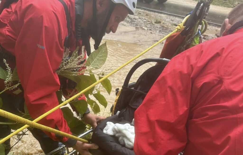 Two men with a rescue unit save a baby from flood waters.