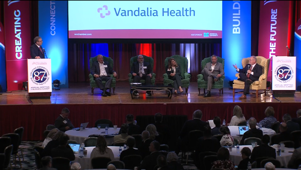 A group of health professionals sit on a stage for a health panel.