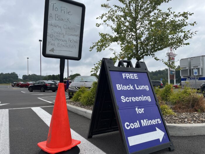 Two signs with arrows point to different resources available at a black lung health fair.